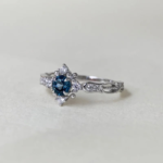 Swan Pırlanta London Blue Topaz taşı bulunan zarif tektaş yüzük, çevresinde küçük pırlantalarla çerçevelenmiş gümüş ayarlarıyla zarif bir görünüm sunar; Osmanlı çini ilhamı ve vintage hatlar dikkat çeker.
