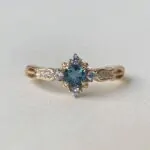 Swan Pırlanta London Blue Topaz tektaş yüzük, altın renkli ayar üzerinde mavi taş ve yanındaki parlak pırlantalarla zarif bir tasarım.