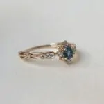 London Blue Topaz taşıyla bezenmiş, lale ve yıldız motifli tektaş yüzük; 14 ayar sarı altın, yan taşlar pırlanta ve zarif işçilikle Swan Pırlanta tasarımı.